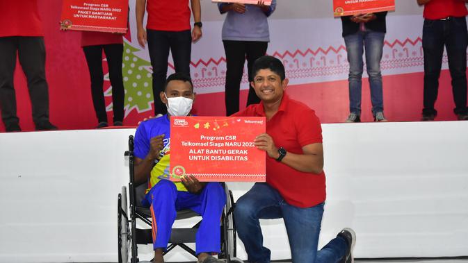 Direktur IT Telkomsel Bharat Alva (kanan) secara simbolis memberikan bantuan berupa alat bantu gerak untuk penyandang disabilitas dalam rangkaian Roadshow Natal 2022 di Kota Ambon, Kamis (8/12). (Dok. Telkomsel)
