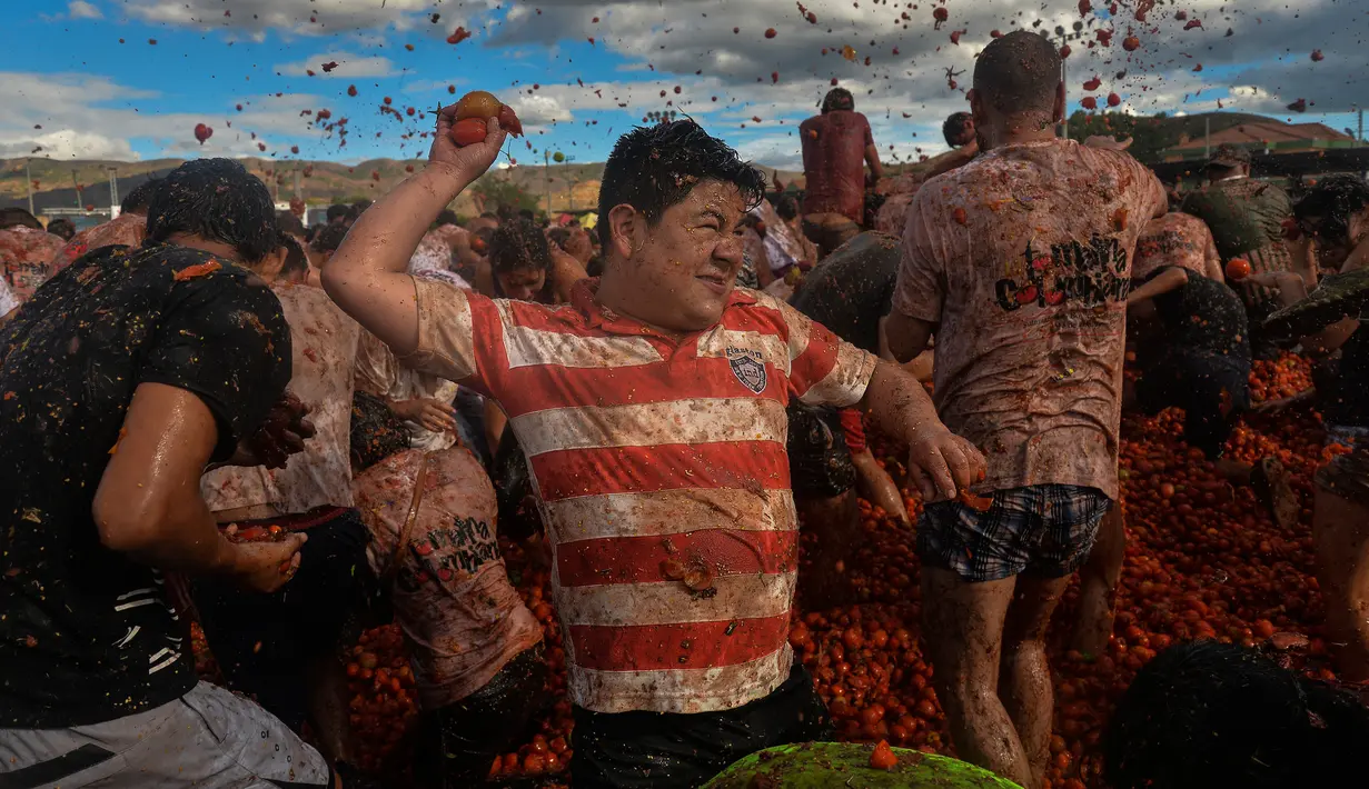 Peserta saling lempar saat perang tomat dalam Festival Tomatina di Sutamarchan, Boyaca, Kolombia, Minggu (2/6/2019). Perang tomat ini digelar selama tiga hari berturut-turut. (Diana SANCHEZ/AFP)
