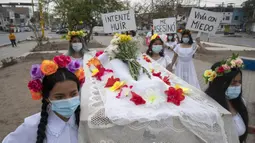 Rombongan teater Vichama melakukan prosesi kamar mayat berjudul "Kami Ingin Diri Sendiri Hidup!" sambil membawa tubuh tiruan dan menampilkan tanda-tanda kiasan pada malam Hari Anti Kekerasan Terhadap Perempuan di Villa El Salvador, Lima, Peru, 24 November 2021. (Cris BOURONCLE/AFP)