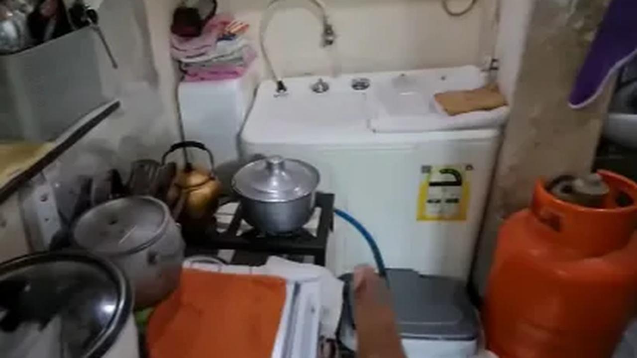 Di pojok ruangan, terdapat mesin cuci. Di sampingnya, terlihat area dapur milik Jaya.