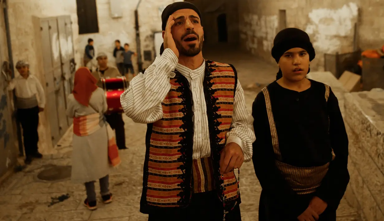 Kelompok pemuda Palestina berpakaian tradisional berteriak membangunkan kaum muslim untuk sahur di Kota Tua Yerusalem, Selasa (5/6). Dalam tradisi Musaharati ini biasanya mereka memakai alat musik sambil menyanyikan lagu-lagu religius. (AP/Mahmoud Illean)