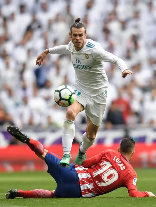 Pemain depan Real Madrid, Gareth Bale melompati bek Atletico Madrid Lucas Hernandez saat pertandingan La Liga Spanyol di stadion Santiago Bernabeu di Madrid (8/4). (AFP/Gabriel Bouys)