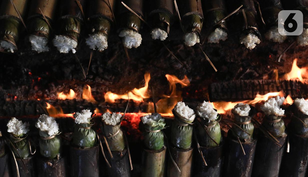 Pekerja membakar lemang atau beras ketan yang dimasukan ke bambu di kawasan Senen, Jakarta, Rabu (29/3/2023). (Liputan6.com/Herman Zakharia)