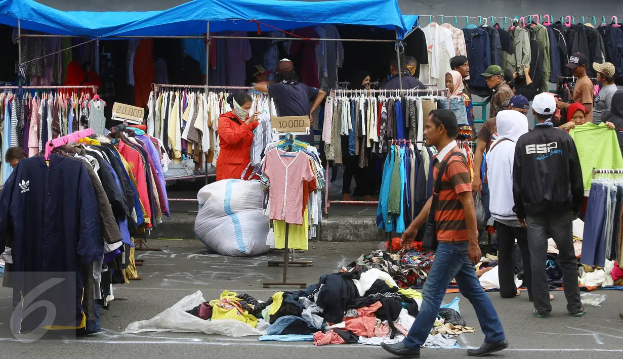 Pedagang menjajakan pakaian bekas di kawasan Pasar Senen, Jakarta, Senin (23/1). Pascakebakaran beberapa hari lalu, para pedagang terpaksa berjualan di luar gedung, meskipun menutup jalan dan mengganggu arus lalu lintas. (Liputan6.com/Immanuel Antonius)