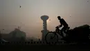 Warga mengedarai becak sepeda melewati sebuah pusat perbelanjaan ditengah kabut tebal polusi perayaan Diwali di New Delhi, India (31/10). Dalam mengurangi polusi ini pemerintah setempat akan memasang pemurni udara. (Reuters/Adnan Abidi)