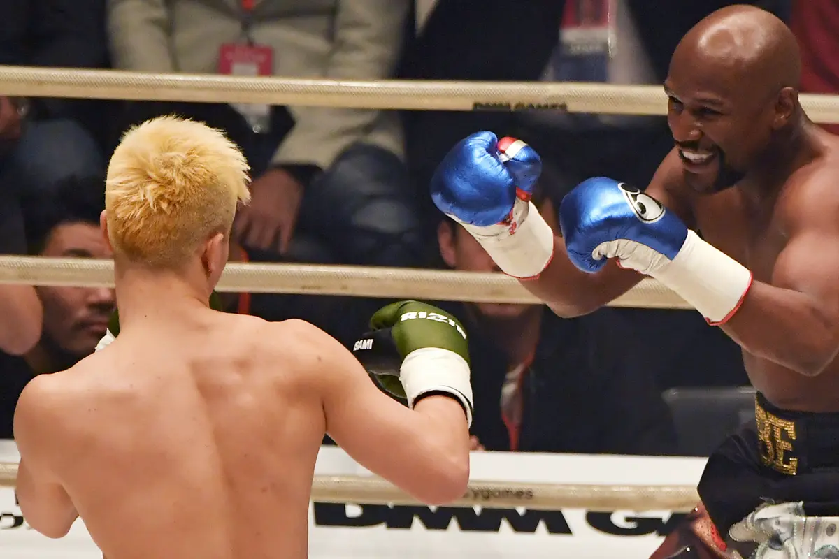 Petinju, Floyd Mayweather, berusaha memukul kickboxer, Tenshin Nasukawa, pada laga eksebisi di Saitama Super Arena, Saitama, Senin (31/1). Tanding dengan aturan tinju, Mayweather menang TKO di ronde pertama. (AFP/Toshifumi Kitamura)