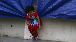Seorang anak terlihat asyik bermain dengan celah terpal di pengungsian Sinabung, Desa Batu Karang, Medan, Sabtu (4/7/2015). Sebanyak 1254 jiwa dari desa Gursinayan sudah mengungsi selama 1 bulan. (Liputan6.com/JohanTallo)