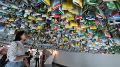 Seorang wanita melihat instalasi seni gantung sekelompok seniman yang terbuat dari sisa-sisa plastik, kaleng dan wadah di sebuah pameran "Reduce the Litter" di Pusat Kebudayaan Prancis di Hanoi (15/7/2019). Pameran ini mengambil perspektif tentang produksi dan konsumsi. (AFP Photo/Nhac Nguyen)