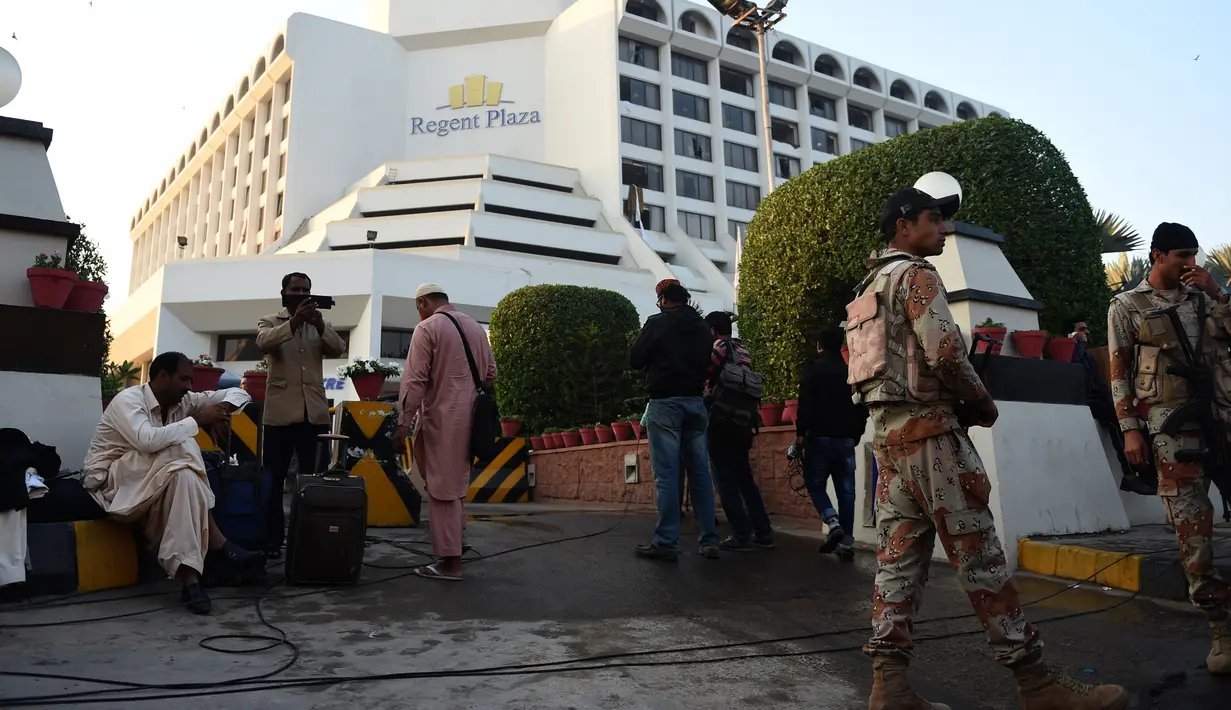 Petugas berjaga di lokasi kebakaran sebuah hotel mewah di kota Karachi, Pakistan, Senin (5/12). Wali Kota Karachi Waseem Akhtar mengatakan penyebab kebakaran ini masih belum diketahui secara pasti. (RIZWAN Tabassum/AFP)