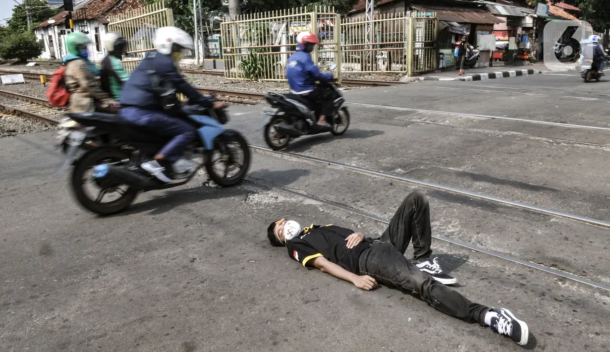 Pengendara motor menyaksikan aksi teatrikal di perlintasan kereta api sebidang, Kemayoran, Jakarta, Rabu (14/10/2020). PT KAI Daop 1 menggelar sosialisasi dan aksi teatrikal dalam rangka meningkatkan kesadaran pengendara saat melintasi perlintasan sebidang. (merdeka.com/Iqbal Nugroho)