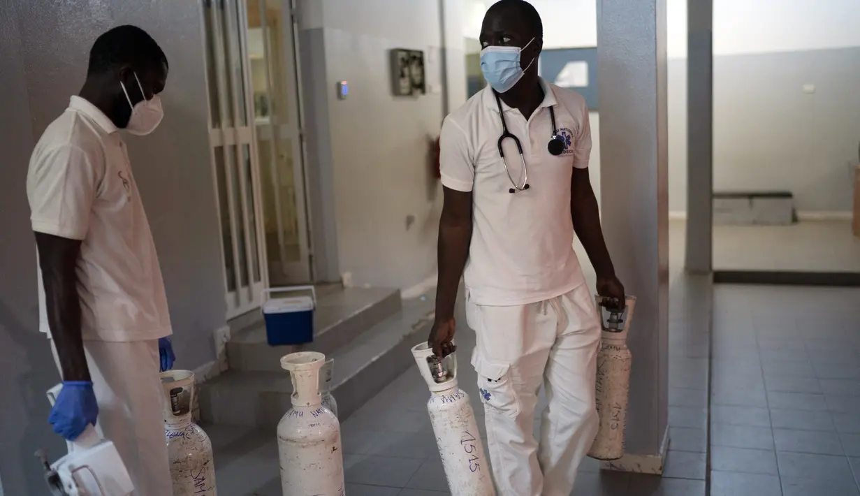 Mobile Emergency Care Service (SAMU) membawa botol oksigen ke ambulans mereka di Dakar, Senegal, pada 5 Agustus 2021. Layanan ambulans di negara Afrika Barat, Senegal, mengatakan sekitar 90 persen panggilan mereka saat ini merespons pasien COVID-19 yang kesulitan bernapas. (AP Photo/Leo Correa)