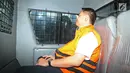 Tersangka anggota DPR Fayakhun Andriadi mengenakan rompi oranye berada di mobil tahanan usai menjalani pemeriksaan di Gedung KPK, Jakarta, Rabu (28/3). (Liputan6.com/Herman Zakharia)