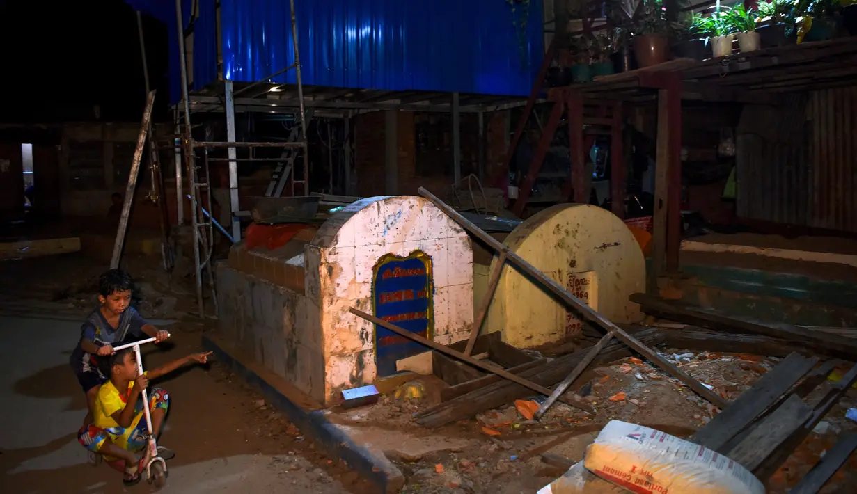 Anak-anak bermain di area kuburan di Phnom Penh, Kamboja pada 21 Juni 2019. Pemakaman menjadi tempat peristirahatan abadi bagi orang mati, tetapi area pemakaman ini menjelma sebagai tempat tinggal untuk bertahan hidup bagi mereka yang didera kemiskinan. (TANG CHHIN Sothy/AFP)