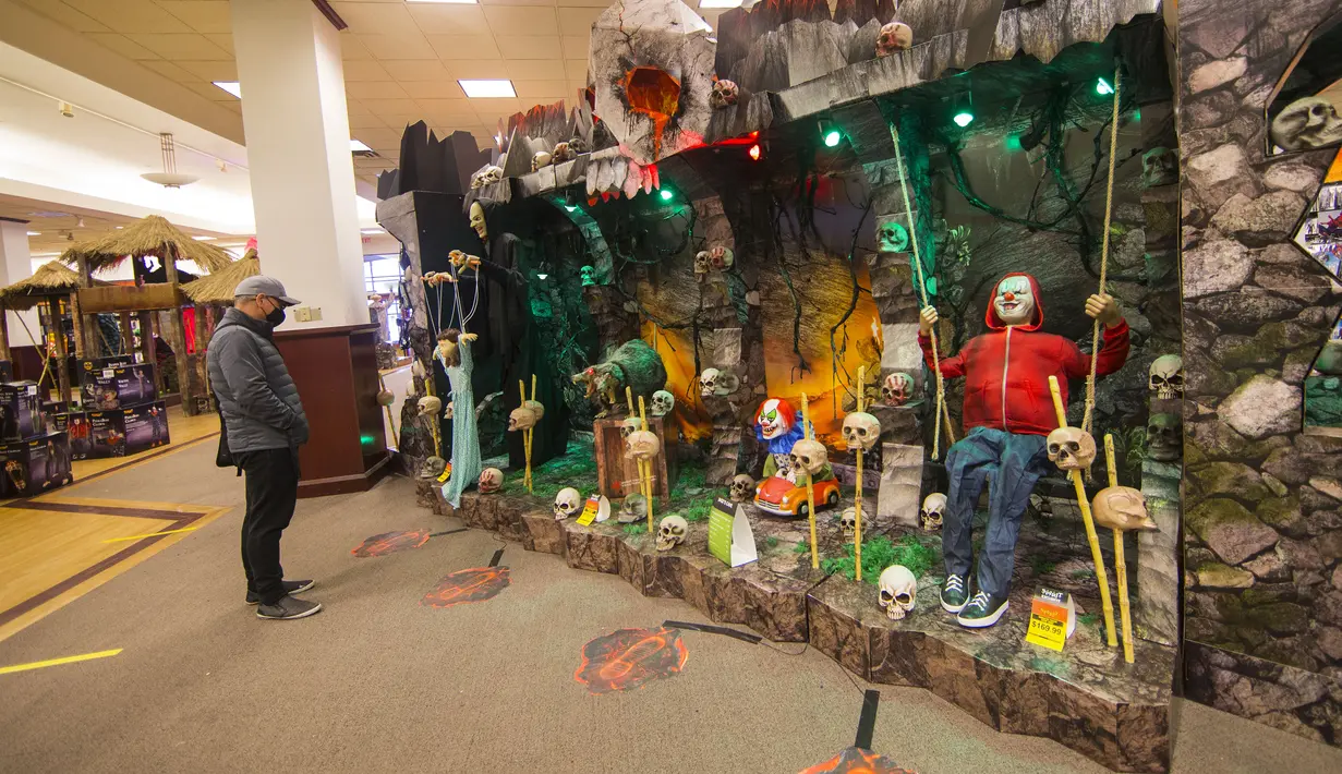 Seorang pria yang mengenakan masker mengamati berbagai dekorasi bertema Halloween di sebuah toko di Mississauga, Ontario, Kanada, pada 29 Oktober 2020. Warga Ontario mulai berbelanja dekorasi dan menghias rumah mereka untuk menyambut Halloween. (Xinhua/Zou Zheng)