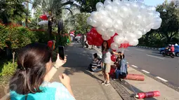 Warga berfoto dengan balon merah putih di halaman Balai Kota DKI Jakarta, Selasa (9/5). Ada yang berbeda pagi ini, Gubernur DKI Basuki Tjahaja Purnama (Ahok) tidak ke Balai Kota terlebih dulu menjelang sidang pembacaan putusan. (Liputan6.com/Johan Tallo)