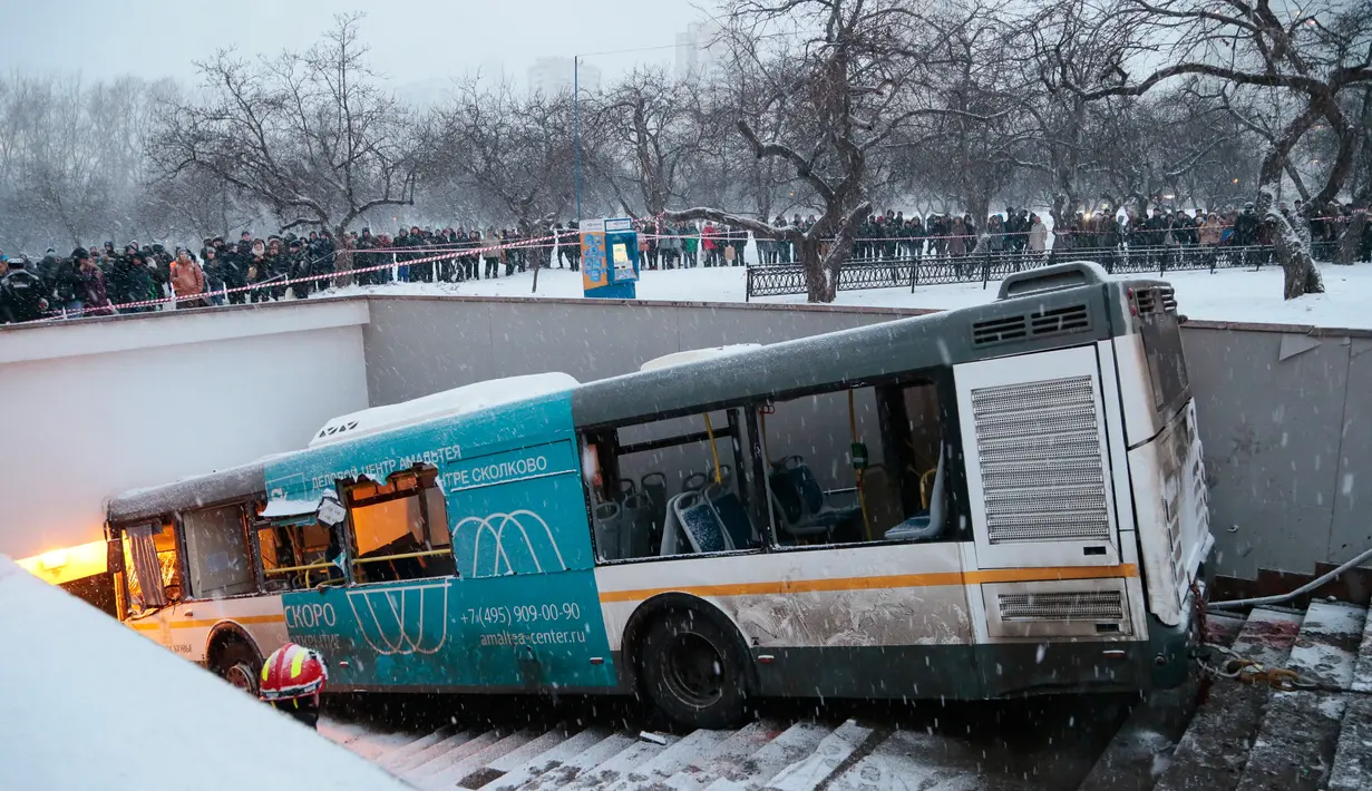 Sejumlah orang melihat lokasi sebuah bus yang hilang kendali dan masuk ke dalam tangga menuju jalan bawah tanah di Moskow, Rusia, Senin (25/12). Bus menerobos underpass yang sedang dilalui banyak pejalan kaki hingga menewaskan 4 orang (AP/Ivan Sekretarev)