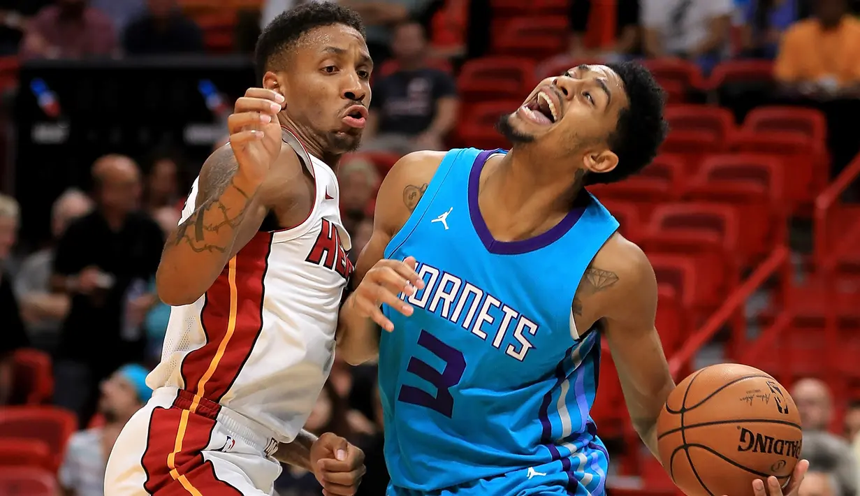 Pebasket Hornets, Jeremy Lamb (kanan) kesulitan melewati adangan pebasket Miami Heat, Rodney McGruder (kiri) pada laga NBA pre-season di American Airlines Arena, Miami, (9/10/2017). Miami Heat menang 109-106. (Mike Ehrmann/Getty Images/AFP)
