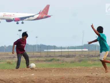 Anak-anak bermain bola di kawasan proyek perluasan landasan pacu atau Runway 3A Bandara Soekarno-Hatta (Soetta), Rawa Bokor, Tangerang, Banten, Selasa (2/7/2019). Mereka memanfaatkan lahan kosong yang belum dikerjakan pihak kontraktor untuk bermain bola. (merdeka.com/Arie Basuki)