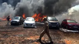 Petugas pemadam kebakaran berdiri dekat deretan mobil yang terbakar di area parkir pameran dirgantara Aero India 2019, Bangalore, India, Sabtu (23/2). Pejabat pemadam kebakaran menduga rumput kering memicu terjadinya kebakaran. (AP Photo/Parthi Bhan)