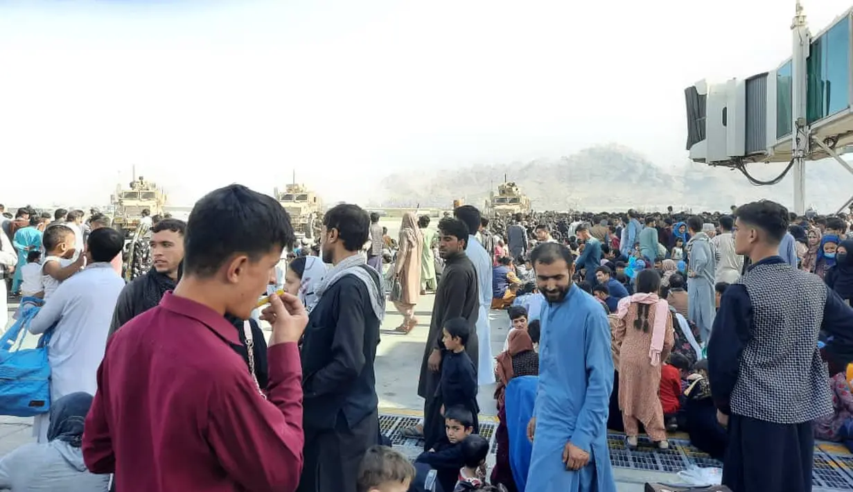 Warga Afghanistan berkerumun di landasan bandara Kabul pada 16 Agustus 2021, untuk melarikan diri dari negara itu ketika Taliban menguasai Afghanistan setelah Presiden Ashraf Ghani melarikan diri dan mengakui pemberontak telah memenangkan perang 20 tahun. (AFP Photo)