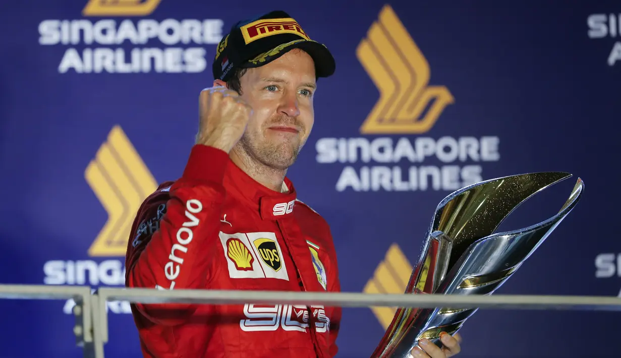 Pembalap Ferrari Sebastian Vettel berselebrasi di podium setelah memenangkan balapan Formula Satu (F1) Grand Prix Singapura di Sirkuit Jalan Marina Bay, Singapura (22/9/2019). Vettel berhasil menjuarai balapan dengan catatan waktu 1 jam:58menit:33.667 detik. (AP Photo/Vincent Thian)