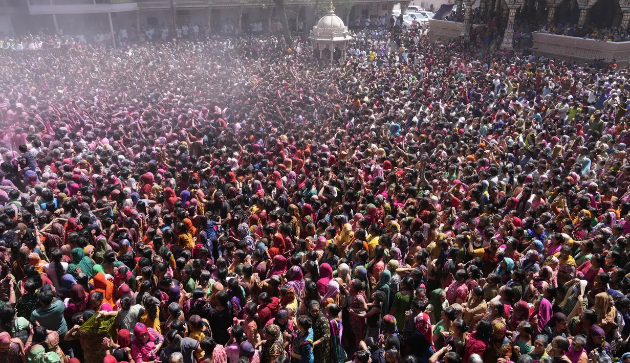 Umat Hindu bersorak saat bubuk berwarna dan air disemprotkan selama perayaan Festival Holi di kuil Kalupur Swaminarayan di Ahmedabad, India (18/3/2022).  Holi, festival warna Hindu, juga menandai datangnya musim semi. (AP Photo/Ajit Solanki)