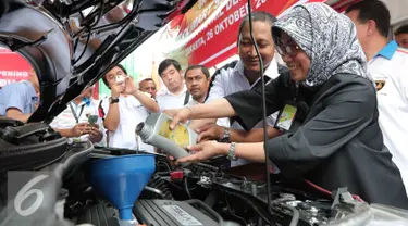 VP Strategi Planning & Business Development PT Pertamina Nina Sulistyowati menuangkan oli saat meresmikan outlet Bright Olimart di SPBU Cakung, Jakarta, Senin (26/10). Outlet ini merupakan pelayanan servis pengendara bermotor. (Liputan6.com/Angga Yuniar)