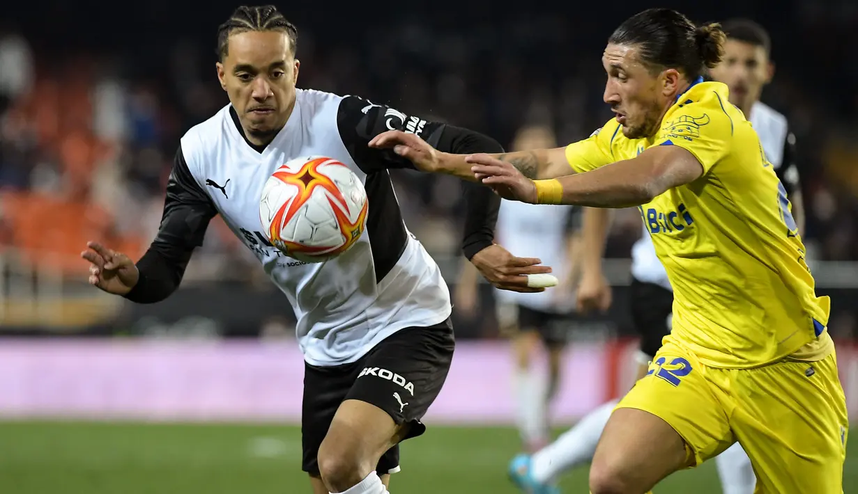 Gelandang Valencia, Helder Costa (kiri) berebut bola dengan bek Cadiz, Pacha Espino selama pertandingan perempat final Piala Raja atau Copa del Rey di stadion Mestalla di Valencia 3/2/2022). Valencia menang tipis atas Cadiz 2-1 dan melaju ke semifinal. (AFP/Jose Jordan)
