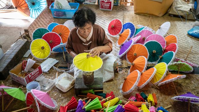 Seorang perajin perempuan merekatkan bagian atas payung di Sentra Pembuatan Payung di Desa Bor Sang, Chiang Mai, Thailand, pada 1 November 2020. Desa Bor Sang, sekitar sembilan kilometer di sebelah timur Kota Tua Chiang Mai, terkenal sebagai daerah pembuat payung kertas. (Xinhua/Zhang Keren)