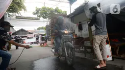 Sejumlah pemuda menyemprotkan cairan disinfektan kepada orang yang akan memasuki RW 10 di kawasan Tanah Kusir, Kelurahan Kebayoran Lama Selatan, Jakarta, Rabu (8/4/2020). Warga menerapkan akses satu pintu masuk pemukiman tersebut untuk mencegah penyebaran corona COVID-19. (merdeka.com/Dwi Narwoko)