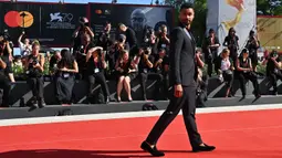 Aktor Inggris Rege-Jean Page tiba untuk pemutaran film 'The Banshees of Inisherin' pada acara Venice International Film Festival ke-79 di Lido, Venesia, Italia, 5 September 2022. Aktor itu mengenakan jas hitam dan celana dengan warna senada. (Andreas SOLARO/AFP)