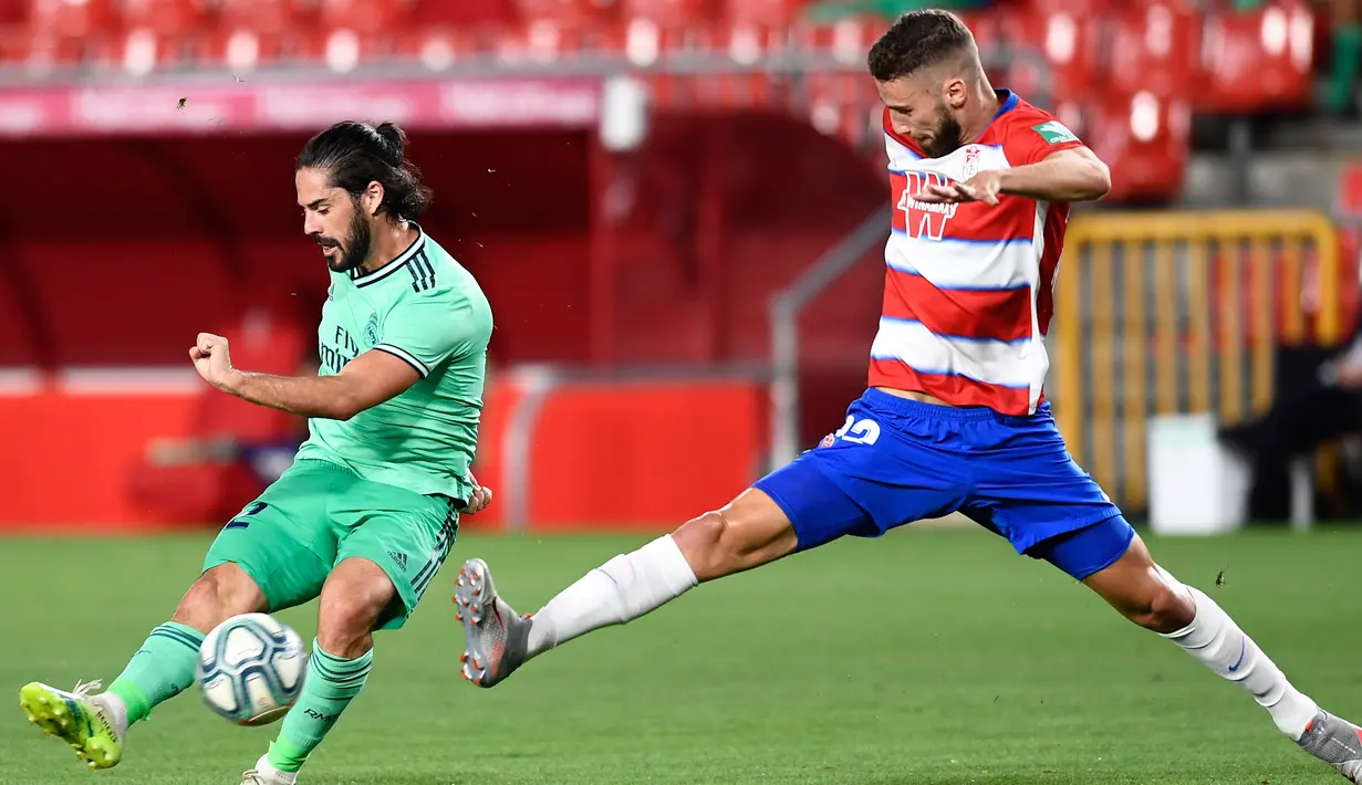 Gelandang Real Madrid, Isco menembak bola dari kawalan pemain Granada, Domingos Duarte pada pertandingan lanjutan La Liga Spanyol di stadion Nuevo Los Carmenes di Granada (13/7/2020). Madrid menang tipis 2-1 atas Granada. (AP Photo/Jose Breton)