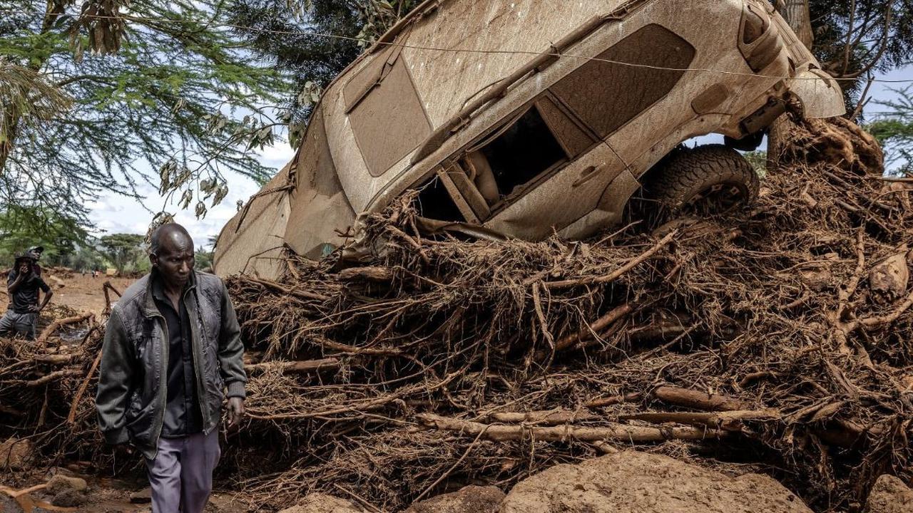 Warga berjalan di dekat sebuah mobil yang tersapu banjir bandang di Desa Kamuchiri, Kota Mai Mahiu, Kenya, Senin (29/4/2024). Terjangan banjir bandang dan tanah longsor di Mai Mahiu, yang menyapu rumah-rumah dan mobil, menewaskan sedikitnya 45 orang dan m