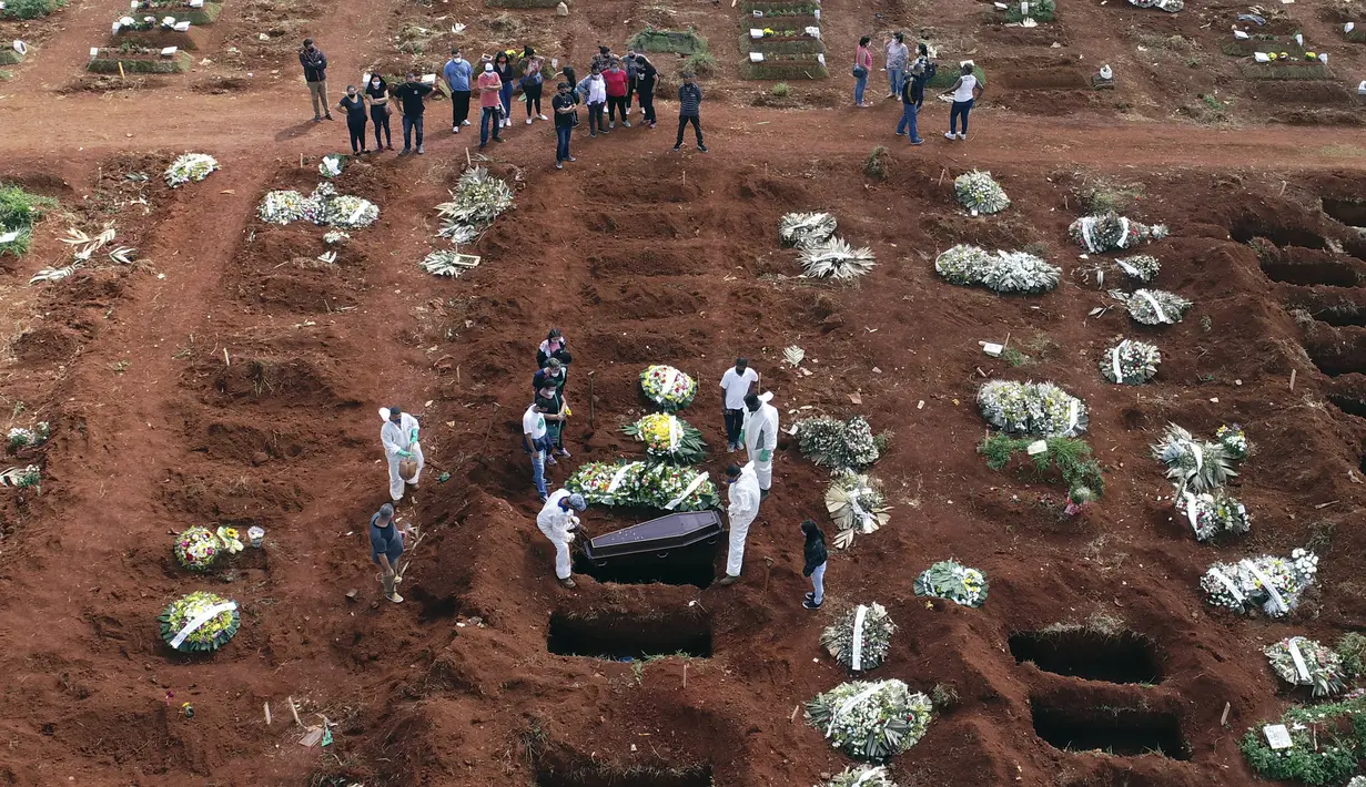 Petugas dengan pakaian pelindung menurunkan peti mati seseorang yang meninggal karena komplikasi COVID-19 ke dalam kuburan di pemakaman Vila Formosa di Sao Paulo, Brasil, Rabu (7/4/2021). Sao Paulo pada Rabu mulai menggali 600 kuburan tambahan setiap hari di pemakaman kotanya (AP Photo/Andre Penner)