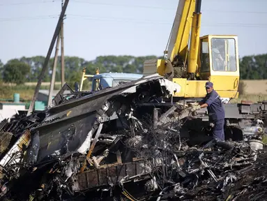 Salah satu anggota Kementerian Darurat Ukraina berusaha memindahkan serpihan puing pesawat MH-17 yang jatuh di desa Hrabove, Donetsk, Ukraina, (20/7/2014). (REUTERS/Maxim Zmeyev)