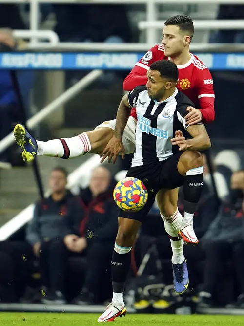 Pemain Newcastle United Callum Wilson (depan) berduel memperebutkan bola dengan pemain Manchester United Diogo Dalot pada pertandingan sepak bola Liga Inggris di St. James' Park, Newcastle, Inggris, Senin (27/12/2021). Pertandingan berakhir imbang 1-1. (AP Photo/Jon Super)