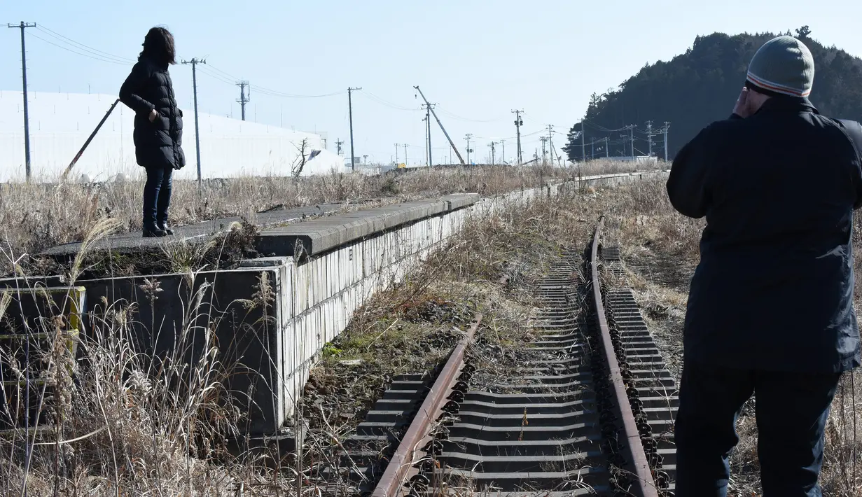 Dua wisatawan melihat Stasiun Tomioka yang ditinggalkan di Namie, Prefektur Fukushima, 11 Februari 2016. Lima tahun pasca bencana nuklir yang dipicu gempa dan tsunami Jepang, banyak wisatawan yang bergabung dengan tur Fukushima (AFP PHOTO/Toru Yamanaka)