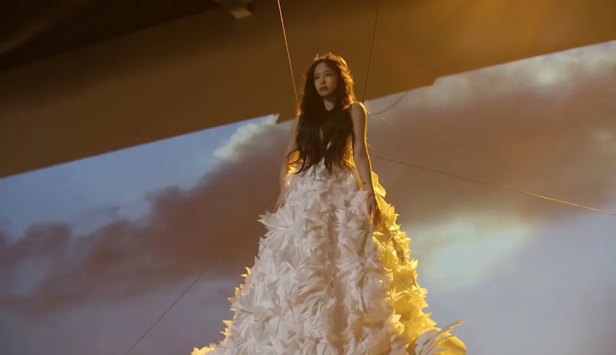 Jennie BLACKPINK dengan gaun putih mewahnya, diikat dengan kabel besi agar terlihat terbang. (Sumber: YouTube/BLACKPINK)