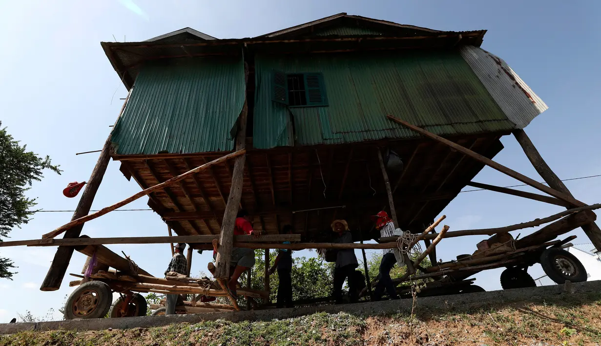 Penduduk desa Kamboja memindahkan sebuah rumah kayu di desa Pon Sang di sisi utara Phnom Penh, Kamboja (26/4/2020). Ini adalah cara bergerak tradisional yang dikumpulkan penduduk desa untuk saling membantu dengan menggunakan traktor dan batang kayu. dengan menjaga rumah tetap utuh. (AP/Heng Sinith)