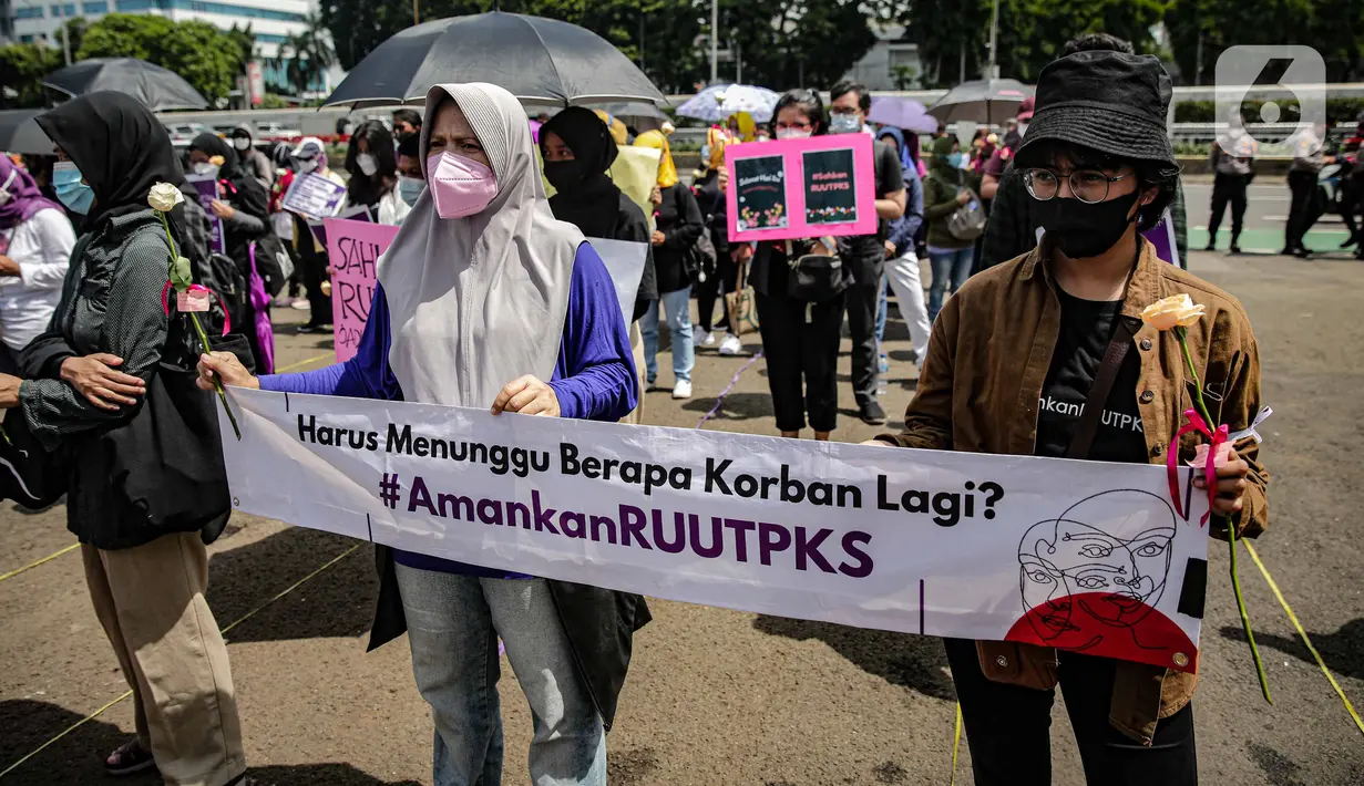 Massa dari Jaringan Pembela Hak Perempuan Korban Kekerasan Seksual membentangkan spanduk di depan Gedung DPR, Jakarta, Rabu (22/12/2021). Mereka mendesak DPR mengesahkan rancangan undang-undang Tindak Pidana Kekerasan Seksual (RUU TPKS) sebagai RUU Inisiatif DPR RI (Liputan6.com/Faizal Fanani)
