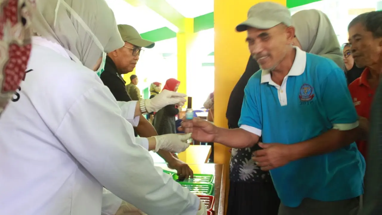 Dimpimpin Kepala Sekolah Dadang Johar Arifin, nampak masyarakat tengah mengantri mendapatkan pembagian hand sanitizer gratis yang diberikan SMKN 1 Garut, Jawa Barat.