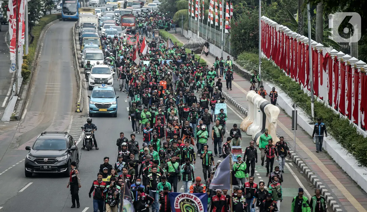 Pengemudi ojek online yang tergabung dalam Koalisi Ojol Nasional melakukan longmarch untuk menggelar aksi di depan Gedung DPR RI, Jakarta, Senin (29/8/2022). Ratusan pengemudi ojek online tersebut menuntut beberapa hal di antaranya payung hukum dan legalitas profesi ojek online serta revisi potongan komisi pendapatan mitra. (Liputan6.com/Faizal Fanani)