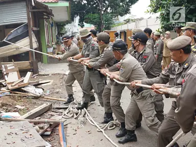 Petugas Satpol PP menarik tali untuk merobohkan bangunan liar di Jalan Desa Semanan, Kalideres, Jakarta Barat, Senin (9/4). Penertiban dilakukan karena bangunan liar tersebut berdiri di atas tanah saluran air. (Liputan6.com/Arya Manggala)