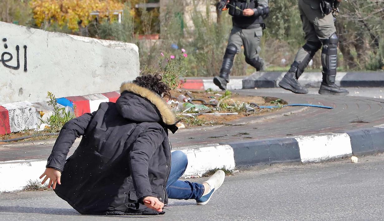 Pria Palestina terjatuh usai ditembak polisi Israel di dekat Ramallah, Tepi Barat, Jumat (15/12). Akibat pernyataan Presiden AS yang mengakui Yerusalem sebagai ibu kota Israel Situasi di perbatasan Palestina-Israel terus memanas. (AFP Photo/Oren Ziv)