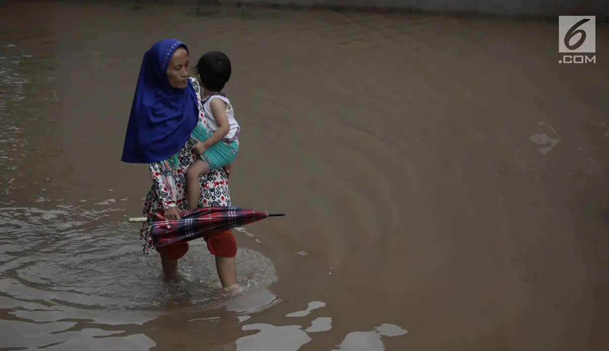 Seorang warga menggendong anak melintasi banjir yang merendam kawasan Cipinang Melayu, Jakarta Timur, Senin (5/2). (Liputan6.com/Arya Manggala)