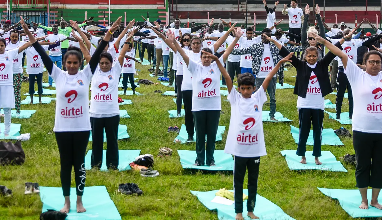 Ratusan warga melakukan gerakan yoga saat mengikuti sesi yoga massal di Stadion Afraha di Nakuru, Kenya (15/6/2019). Acara yoga massal ini untuk memperingati Hari Yoga Internasional. (AFP Photo/Suleiman Mbatiah)