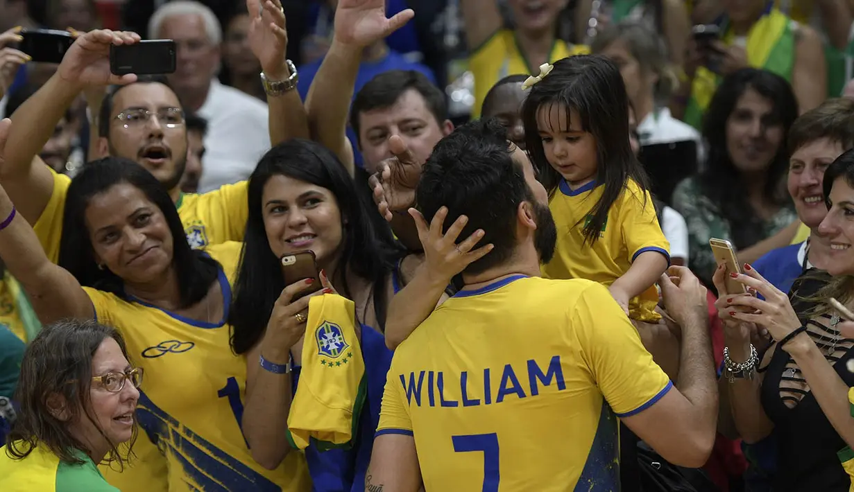 Usai berhasil menaklukkan Rusia, pevoli Brasil, William, langsung menghampiri sang putri yang berada di kursi penonton. (AFP/Juan Mabromata)
