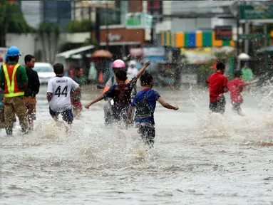 Sejumlah anak berlarian sambil bermain banjir yang merendam kawasan Benhil RT 03 RW 05, Jakarta Pusat, Selasa (21/1). Hujan deras yang mengguyur sejak Selasa dinihari mengakibatkan kawasan tersebut mengalami banjir. (Liputan6.com/Johan Tallo)