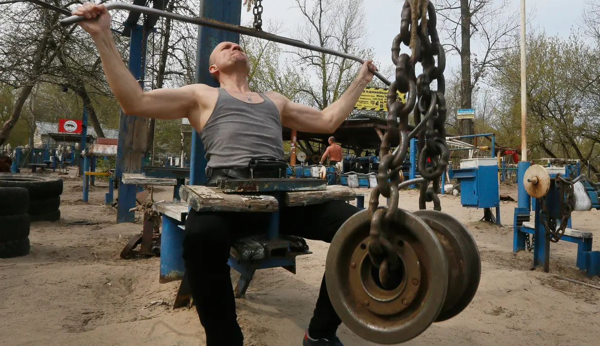 Seorang pria berlatih mengangkat beban di outdoor gym atau pusat kebugaran terbuka di tepi Sungai Dnipro, Kiev, Ukraina, Kamis (18/4). Pusat kebugaran terbuka ini terbilang unik karena memanfaatkan besi tua sebagai alat fitness. (AP Photo/Efrem Lukatsky)