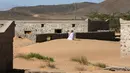 Mantan penduduk Wadi al-Murr, Mohammed al-Ghanbousi berlutut untuk berdoa di gundukan pasir di antara rumah-rumah terlantar di Desa Omani, Wadi al-Murr, Oman, 31 Desember 2020. Penduduk Wadi al-Murr yang sebagian besar mengandalkan pastoral, harus meninggalkan desanya. (MOHAMMED MAHJOUB/AFP)